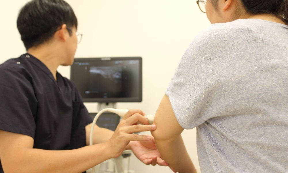 超音波エコーで肘の痛みの原因を検査している接骨院の診察